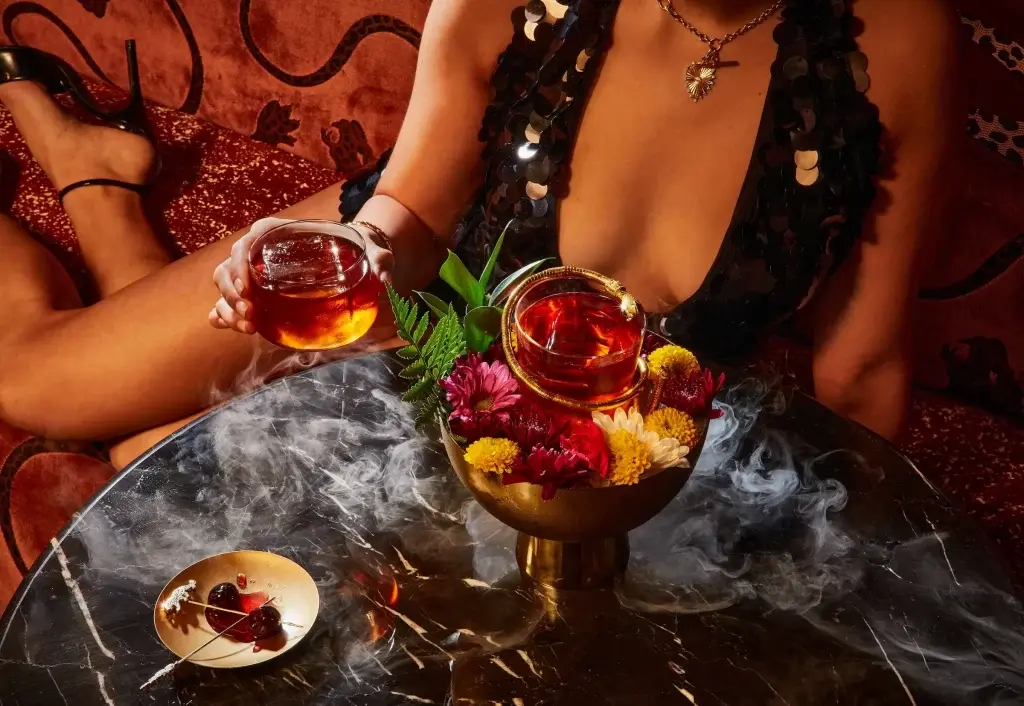 Signature Cocktail at Animl Steakhouse Close-up of a signature cocktail with smoke and garnished with fresh flowers, served at Animl Steakhouse.