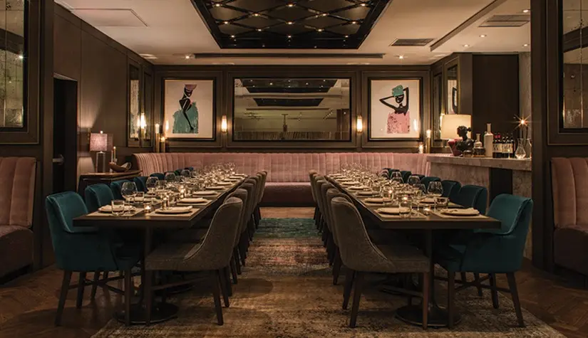 Estia Private Dining – Intimate & Elegant A sophisticated private dining room at Estia, featuring elegant blue and pink seating, candle-lit tables, and modern artwork on the walls.