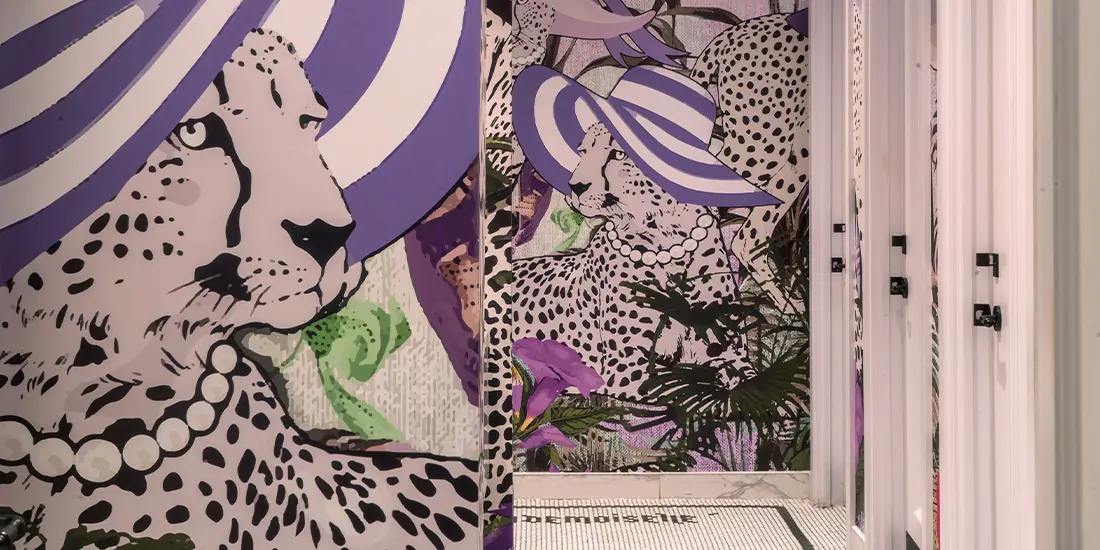 Featuring Mademoiselle Raw Bar Toronto an artistic restroom with bold cheetah fashion illustrations and glossy wall finishes.