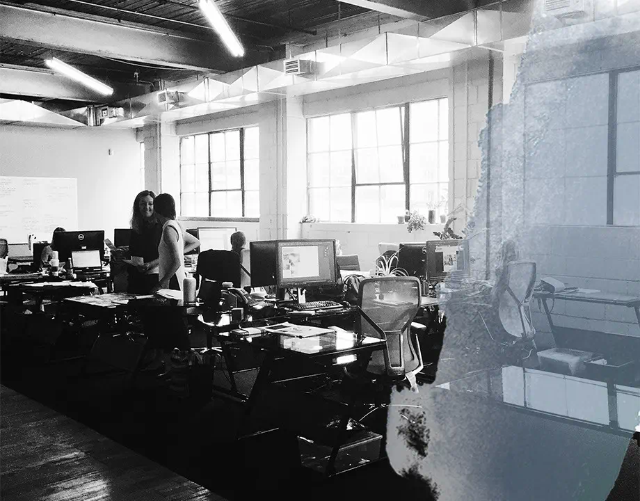 navigate-design-office Black and white photo of Navigate Design’s office, featuring an open-concept layout with employees working at modern desks.