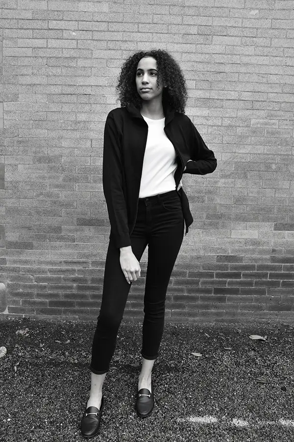 small-womens-hoodes-zip-sw A model in a minimalist black-and-white uniform by Kloth Studio, designed for modern workplaces.